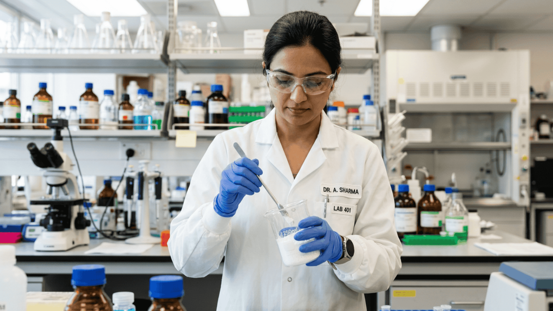 Lab worker mixing white powder in a beaker inside a scientific lab, highlighting calcium carbonate testing and food safety analysis.