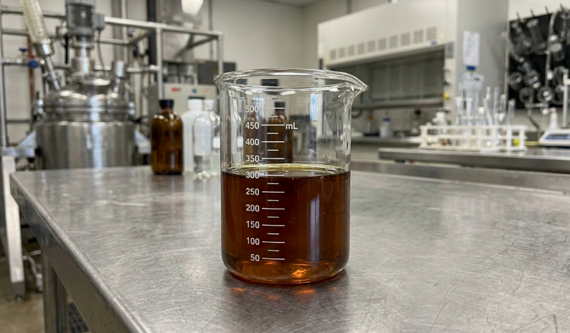 Brown LABSA sample in a graduated glass beaker in an industrial formulation laboratory.